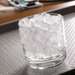 Glass filled with cubelet ice on a textured surface.