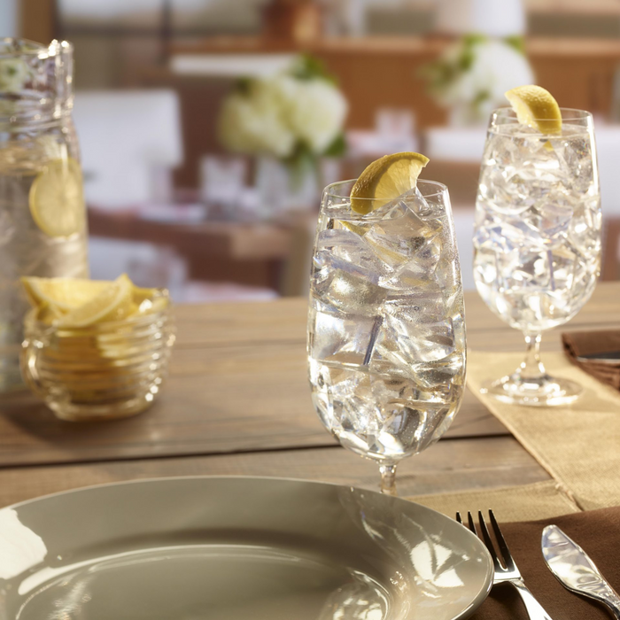 Glasses of water with crescent ice cubes and lemon slices on a wooden table.