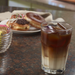Crescent ice cubes in glass with donuts in background.